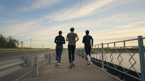 Junge-Sportler-Laufen-Gemeinsam-Im-Freien.-Zwei-Frauen-Und-Ein-Mann-Joggen-Entlang-Der-Autobahn